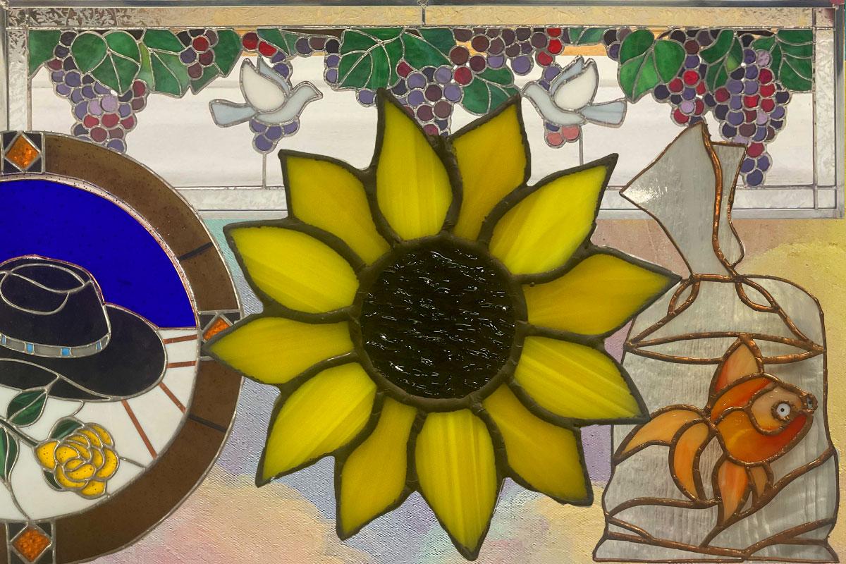 Stained glass piece with a goldfish in a bag, a sunflower and a southwest cowboy hat.